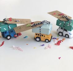 two small toy trucks with boxes tied to them and confetti on the ground