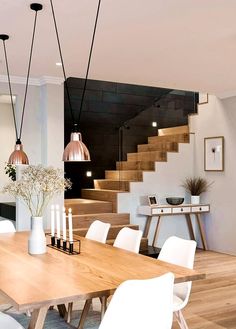 a dining room table with candles and flowers on it in front of stairs that lead up to the second floor