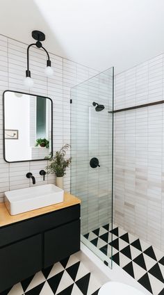 a black and white tiled bathroom with a sink, mirror and standup shower stall