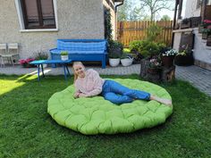 a woman laying on top of a green bean bag chair