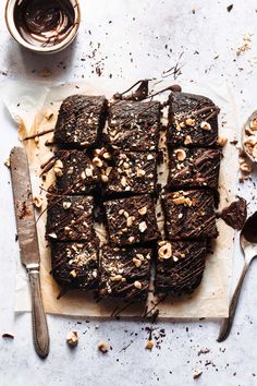 chocolate brownies with walnuts on a cutting board next to a knife and spoon