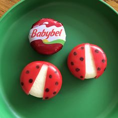 two red and white donuts on a green plate with a babybel candy wrapper