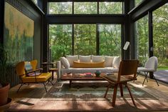 a living room filled with lots of furniture and large glass windows over the top of it