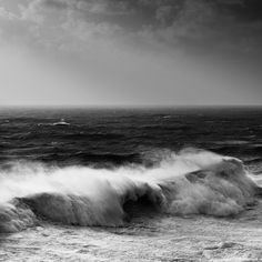 a black and white photo of waves crashing on the beach