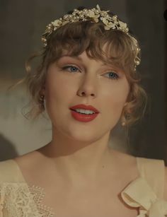 a woman with red lipstick wearing a white dress and a flower headpiece on her head