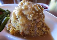 a white plate topped with meat and gravy next to green beans