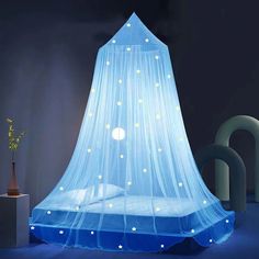 a bed with a blue canopy and white stars on the top, in a dark room