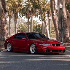 a red sports car parked in front of palm trees