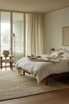 a bed sitting on top of a wooden floor next to a large window with curtains