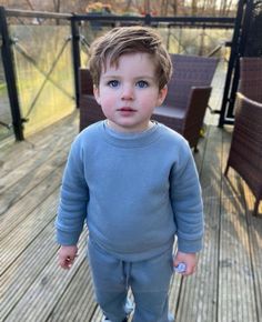 a little boy standing on top of a wooden deck