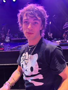 a young man sitting at a piano in front of a stage with purple lighting on it