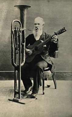 an old black and white photo of a man playing the guitar next to a trumpet