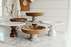 four different types of cake stands on a marble counter with white walls and wood accents