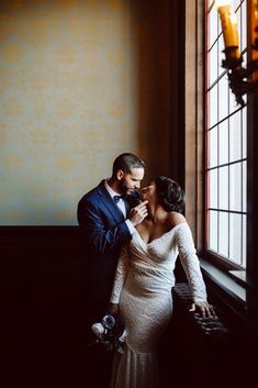 a bride and groom standing in front of a window