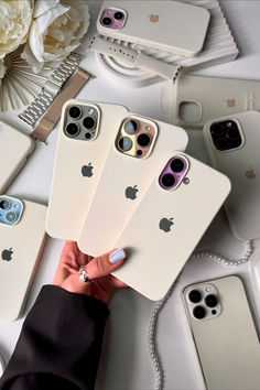 a person holding four iphones in front of several other cell phones on a table