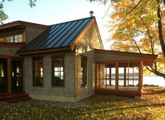 a small house sitting on top of a lush green field next to a body of water