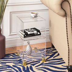 a glass table with a vase on top and a book in the middle next to it