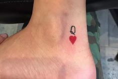 a small red heart tattoo on the left side of the foot, with a black ribbon attached to it