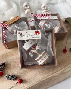 four decorated christmas cookies in a box on a wooden board with pine cones and candy canes