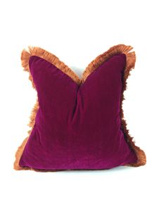 a purple and orange pillow with fringes on the edges, against a white background