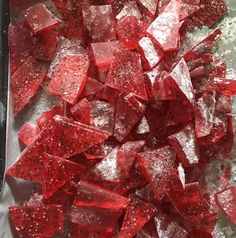 some red pieces of glass sitting on top of a metal pan filled with ice and water