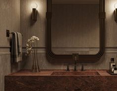 a bathroom sink sitting under a large mirror next to a vase with flowers in it