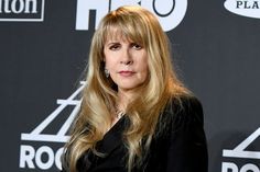 a woman with long blonde hair standing in front of a black background