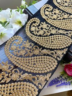 two black and gold brocades sitting on top of a table next to flowers