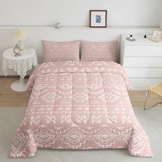 a bed with pink comforter and pillows in a room next to a white dresser