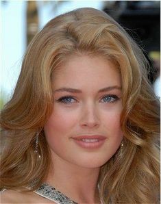 a woman with long blonde hair and blue eyes posing for the camera at an event