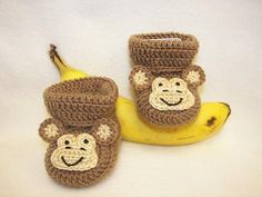 two crocheted monkey slippers are sitting next to a banana on a white surface