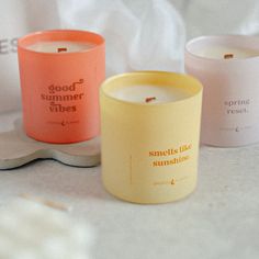 three candles sitting next to each other on top of a white surface with the words good summer vibes printed on them