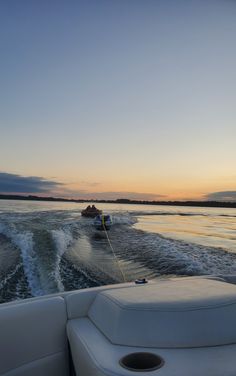 two boats are traveling on the water at sunset or dawn with one boat pulling up to shore