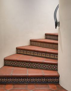 a set of stairs with decorative handrails and tiled steps leading up to the second floor