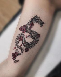 a tattoo on the arm of a woman with a dragon and flowers in red ink