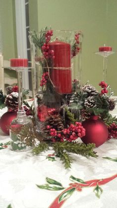 a table topped with red candles and christmas decorations on top of a white table cloth