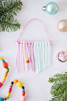 colorful beaded necklaces and ornaments on a white surface with pine branches, ornament