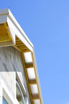 the corner of a building with an open window and sky in the backround