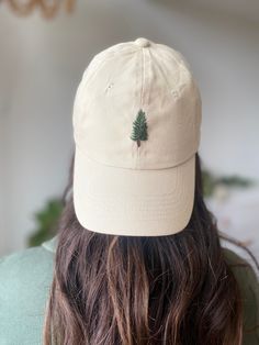 the back of a person wearing a hat with a tree embroidered on it's side