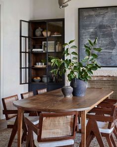 a dining room table with chairs and a potted plant