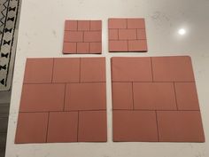 four pieces of pink tile sitting on top of a white table next to each other