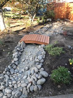 a wooden bench sitting on top of a pile of rocks next to a garden area