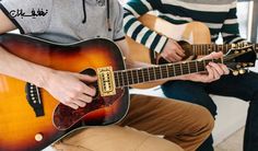 two young men are playing guitars together