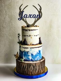 a three tiered cake decorated with deer antlers and the word aaron on top