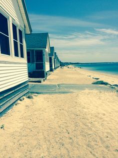 a row of beach houses next to the ocean on a sunny day with blue skies