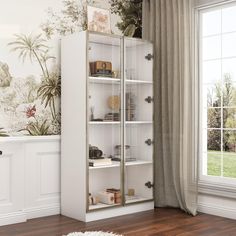 a white bookcase with glass doors in front of a wallpapered background and wooden floor