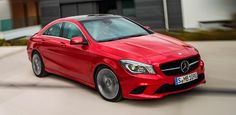 a red mercedes cla driving down the road