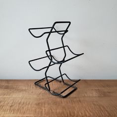 a black metal sculpture sitting on top of a wooden table next to a white wall