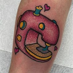 a pink sewing machine tattoo on the leg