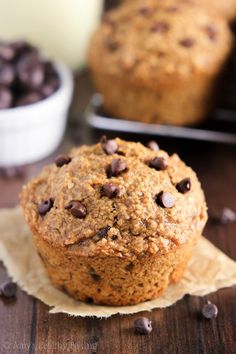 chocolate chip muffins sitting on top of parchment paper next to a glass of milk